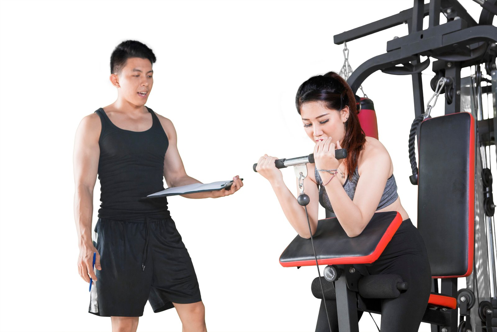 Woman exercising on gym equipment with her coach